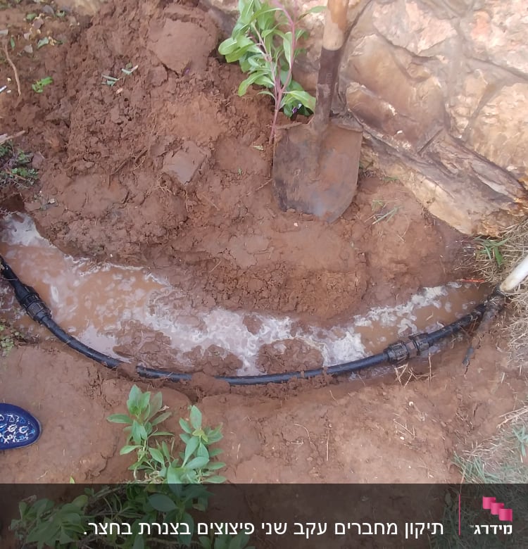 צינור מים דולף באדמה ליד קיר אבן